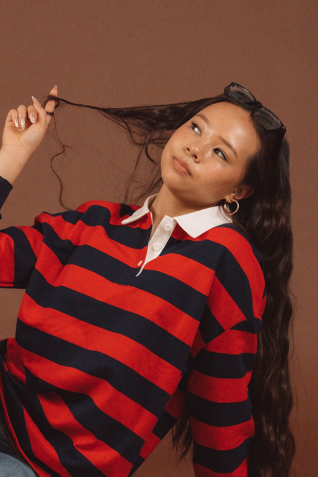 Editorial portrait of Arianna Luong in a striped rugby shirt against a brown backdrop