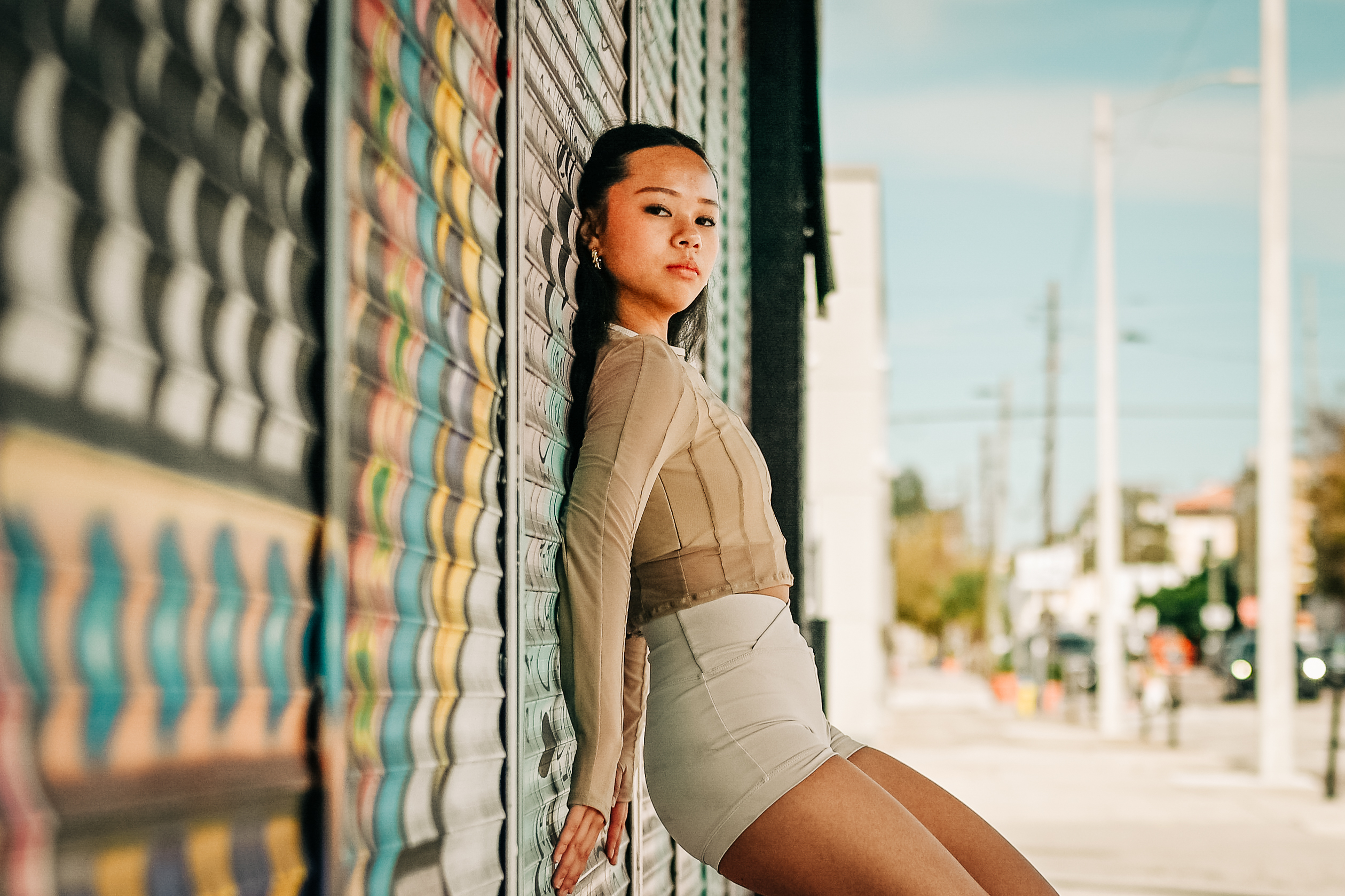 Arianna Luong leaning against a graffiti mural wall in profile