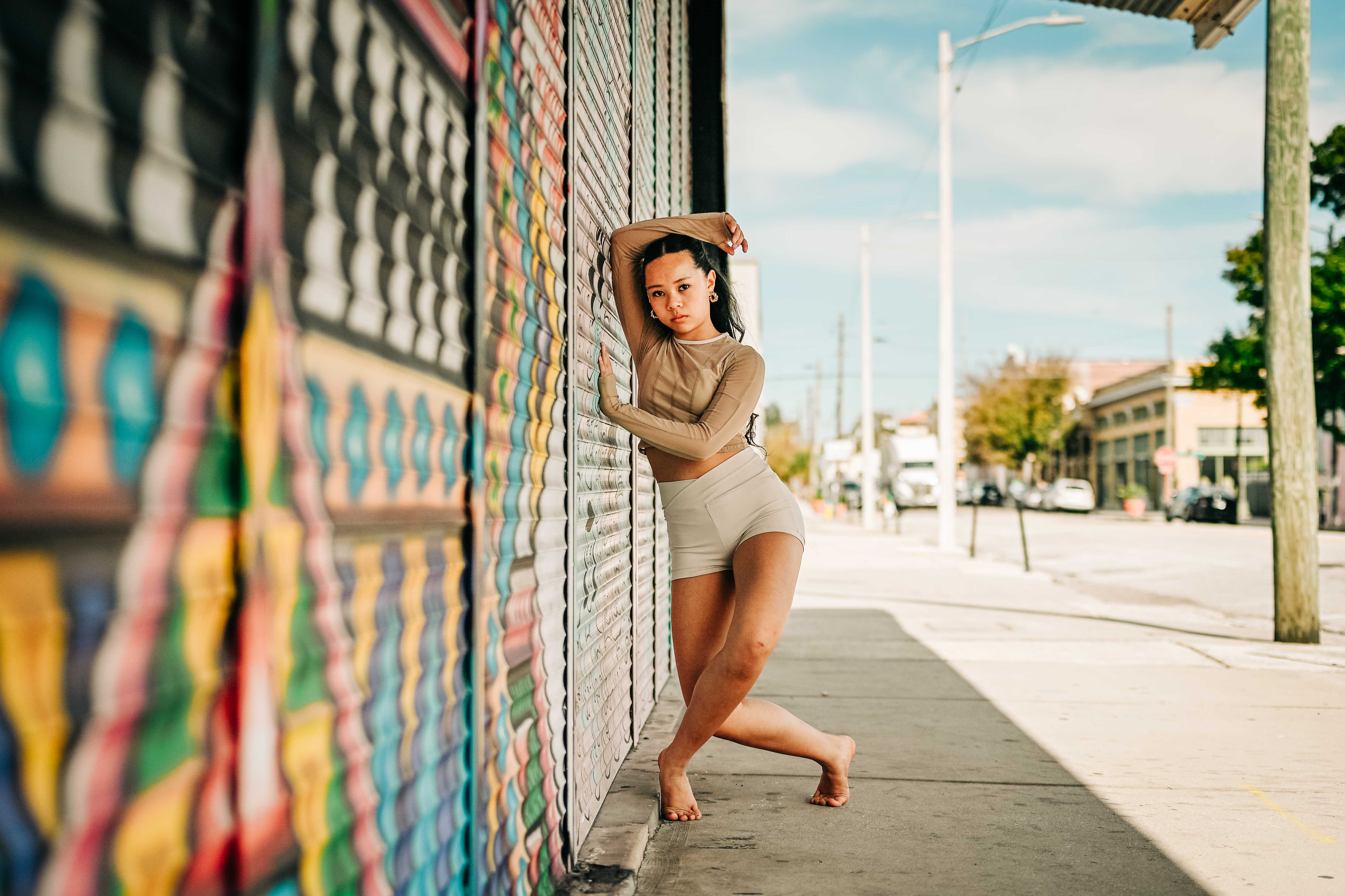 Arianna Luong posed against a colorful graffiti mural with one arm overhead